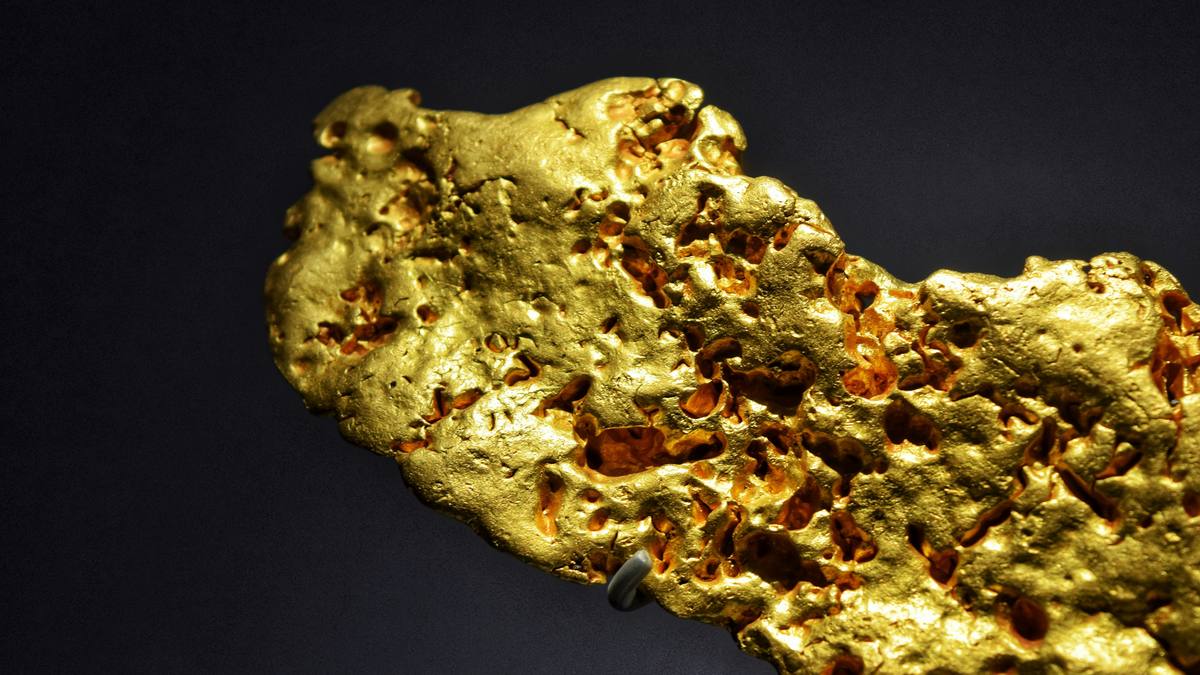 A large raw gold nugget on a black background