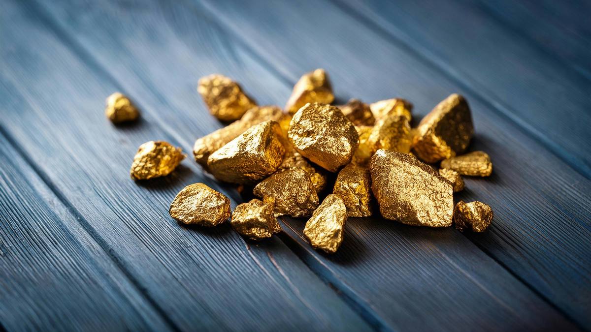 A small pile of raw gold nuggets on a dark wooden table