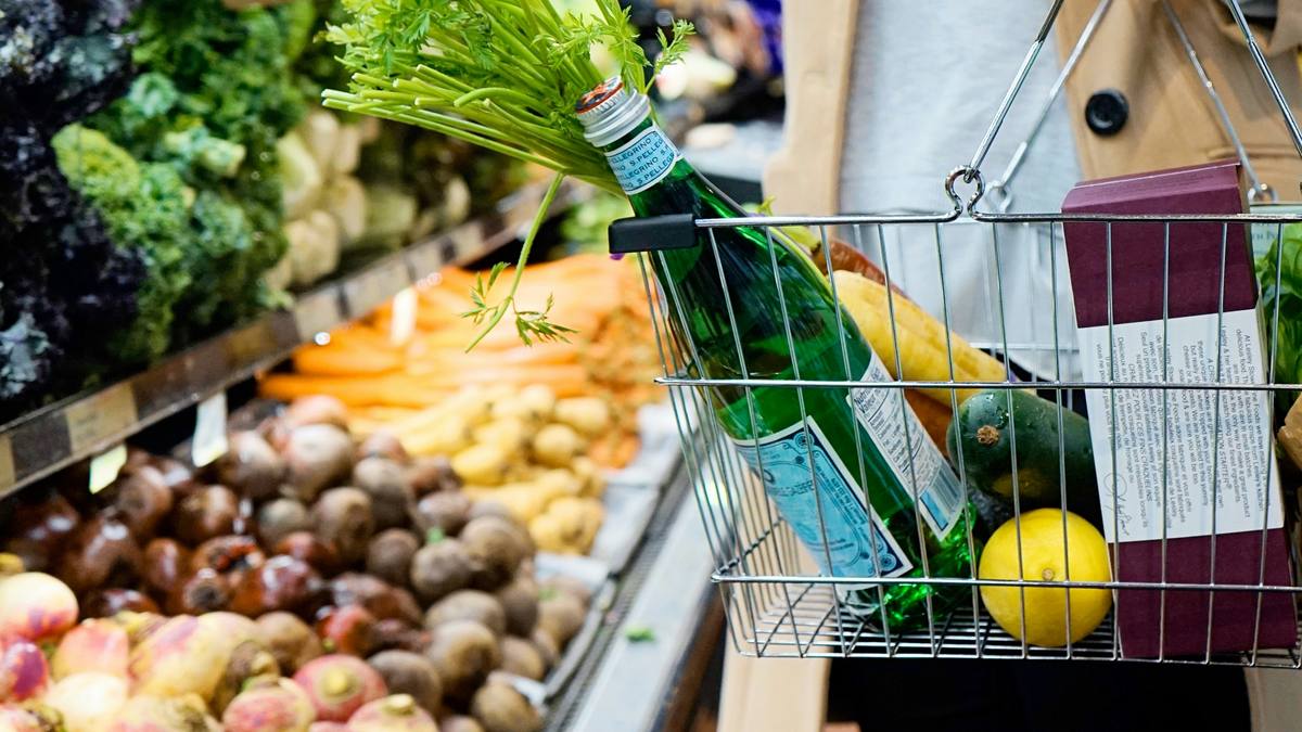 A shopper with a basket of fruit and vegetables in a supermarket